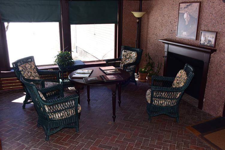 Wicker chairs around table in room with rock covered wall with views outside