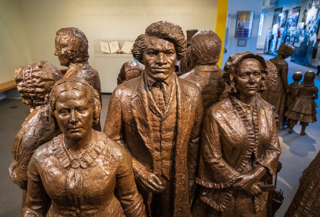 A bronze statue group of people wearing 19th-century clothing.