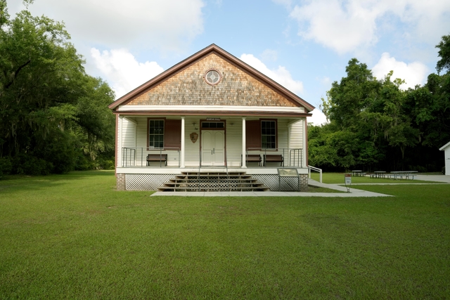 A large white wooden building with red trim and a porch.