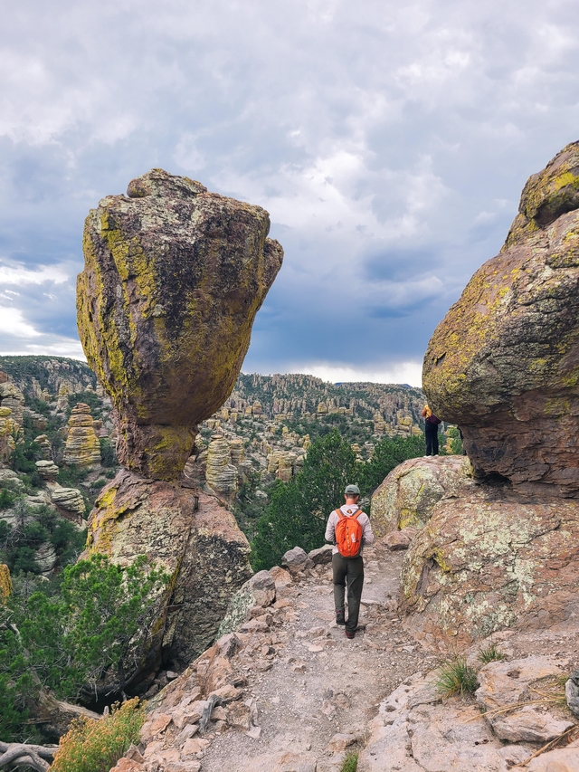 Large rock balanced on a small point with a hiker to the right