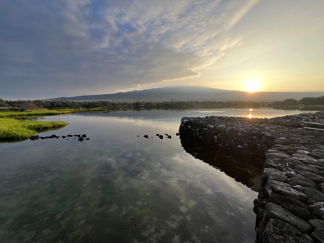 Sun rises over Hualālai volcano as seen from the Kaloko fishpond wall