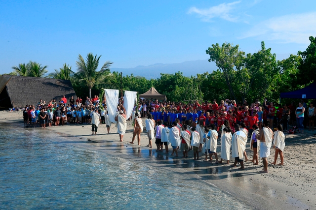 Group of kids form a traditional procession along the beach.