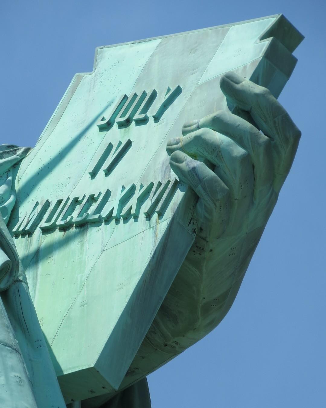 A closeup photo of the left hand and tablet of the Statue of Liberty.